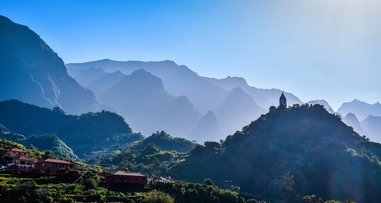Silhouetted landscape with mountains and buildings under a clear sky.