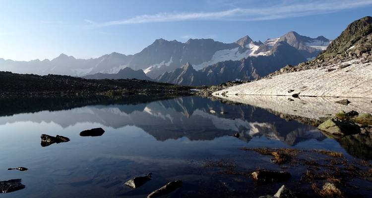 Chaîne de montagnes avec un lac calme reflétant les sommets.