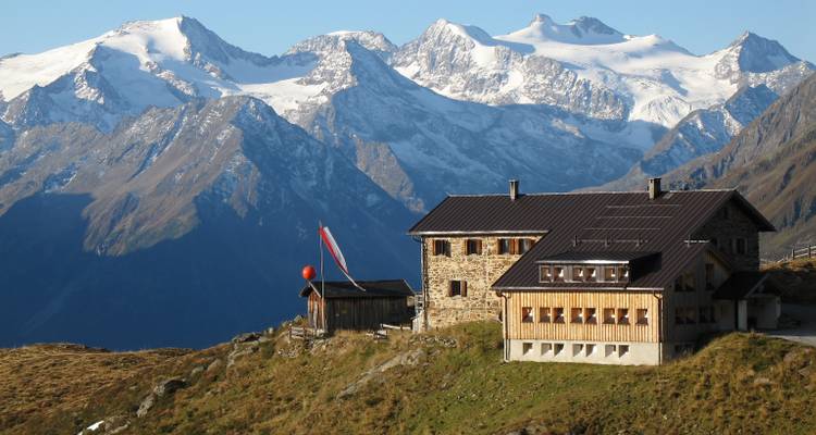 Chalet alpin avec des montagnes enneigées en arrière-plan.