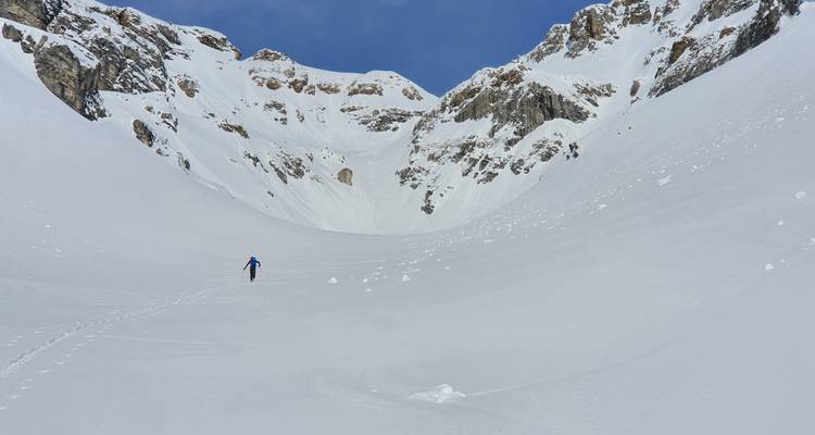 Un randonneur solitaire dans une vaste vallée de montagne enneigée.