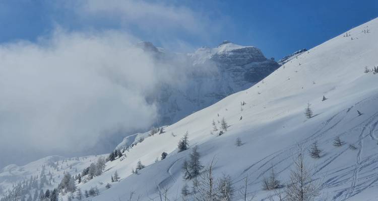 Sommets de montagnes enneigés partiellement obscurcis par les nuages.
