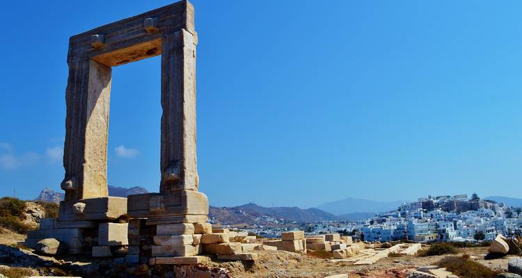 Ruinen eines antiken griechischen Tempels mit einer modernen Stadt im Hintergrund.