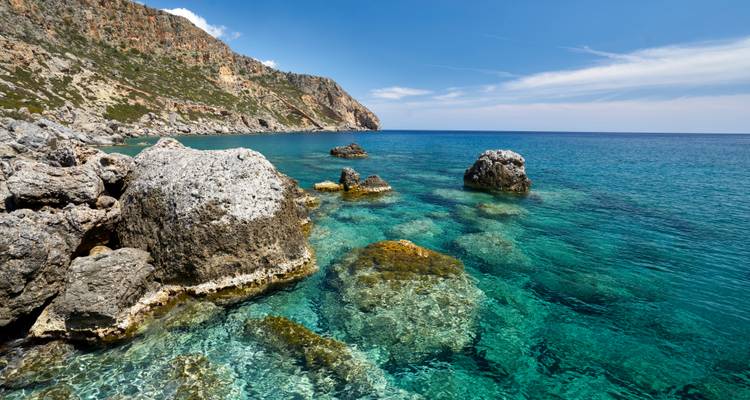 Coastal landscape with rocky shore and clear blue sea.