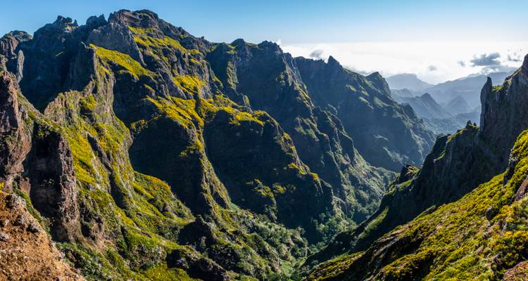 Dramatische Berglandschaft mit steilen Klippen und Grün.