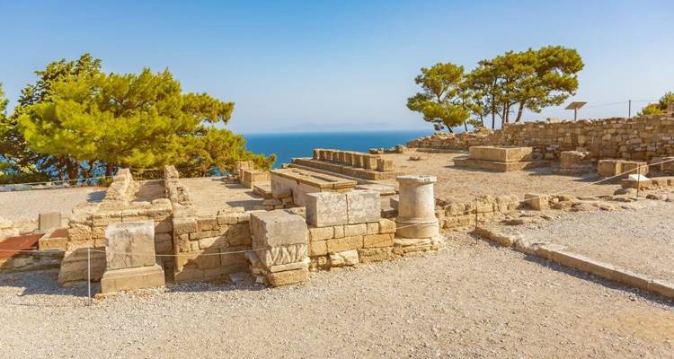 Ancient stone ruins with a view of the sea in the background.