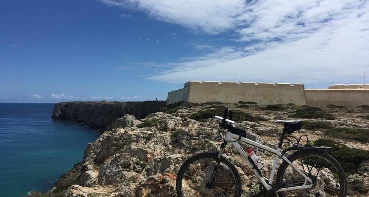 Fahrrad an einer Klippe mit einer historischen Festung mit Blick auf das Meer.