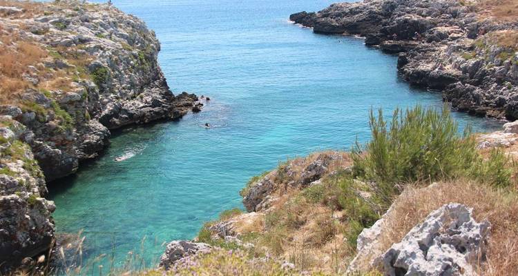 Crique turquoise entourée de falaises rocheuses.