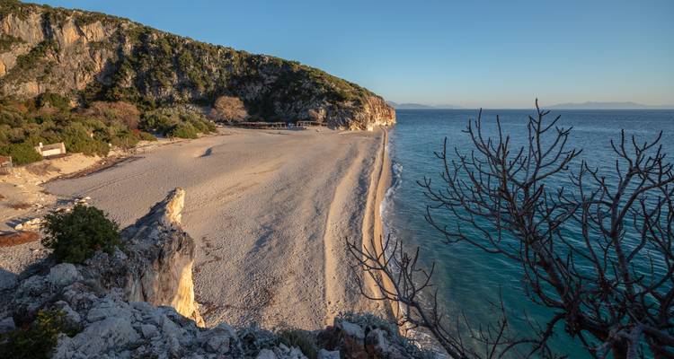 Une plage isolée avec des falaises et une mer bleue claire.