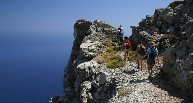 Groupe de randonneurs marchant le long d'une crête côtière rocheuse.