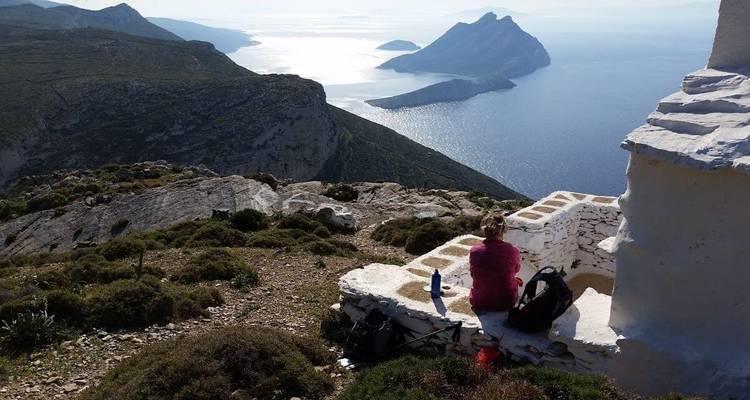 Une personne assise sur un mur de pierre avec une vue panoramique sur l'océan.