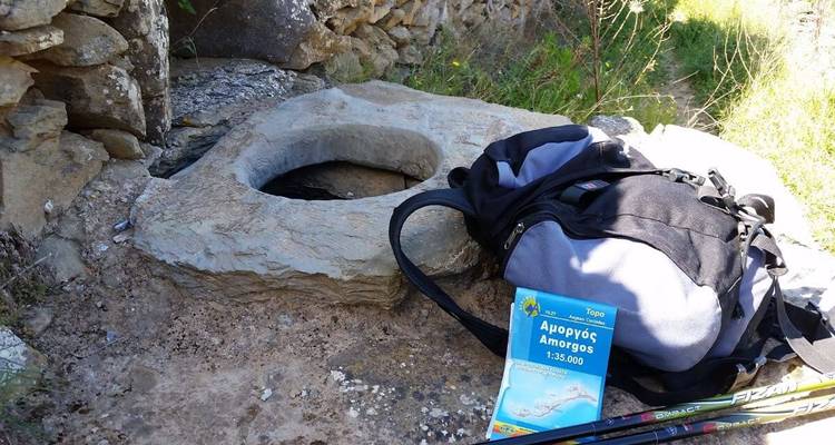 Un gros plan d'un rocher, d'un sac à dos, de bâtons de randonnée et d'une carte d'Amorgos.