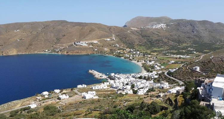 Vue aérienne d'un village côtier avec des bâtiments blancs et une baie bleue.