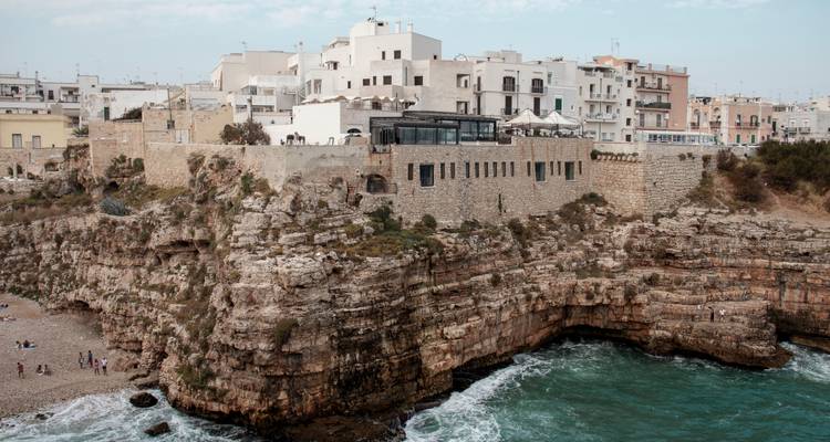 Cala con acantilados escarpados y pueblo histórico compacto.