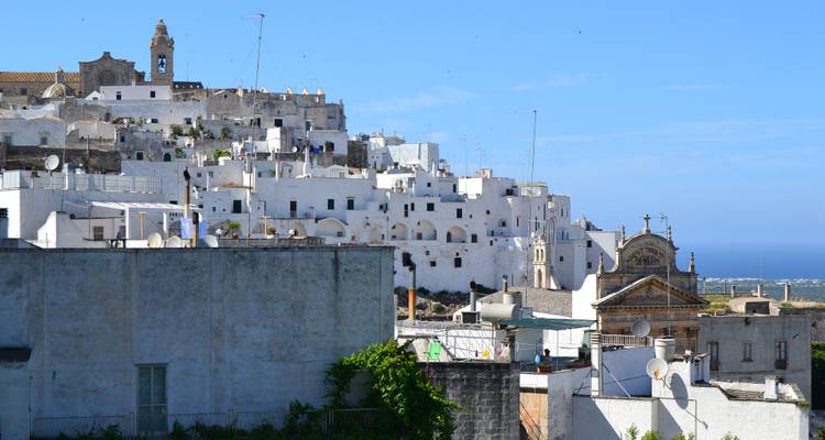 Edificios encalados en una colina con vista al mar de fondo.