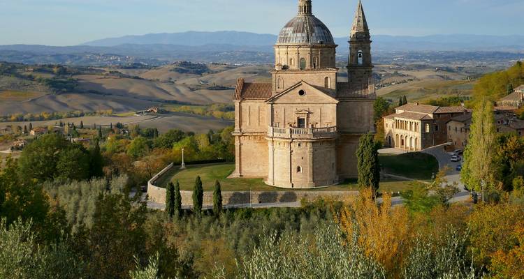 Landschap met een klassieke kerk en glooiende heuvels.