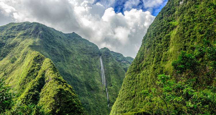 Waterval die naar beneden stroomt door een steile, weelderig groene kloof.
