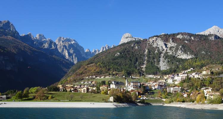 Paysage montagneux avec village et lac sous un ciel dégagé.