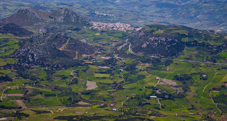 Vue aérienne d'un paysage luxuriant avec des collines et des villages reculés.
