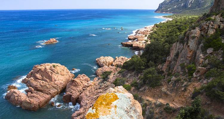 Rocky coastline with clear blue water and greenery.