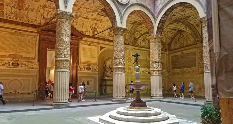 Cour intérieure avec colonnes ornées et personnes.