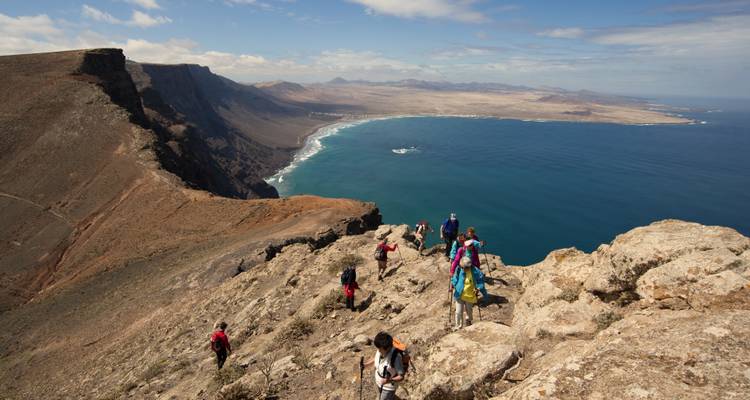 Hikers on a ridge with a vast ocean view.