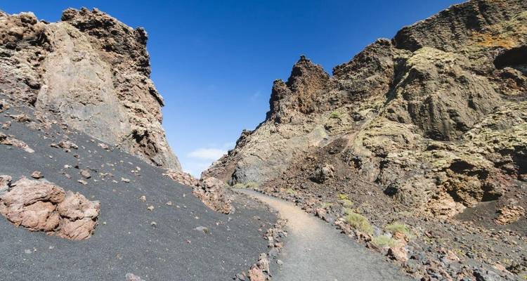 Enge Schlucht mit hohen Felswänden und einem steinigen Pfad.