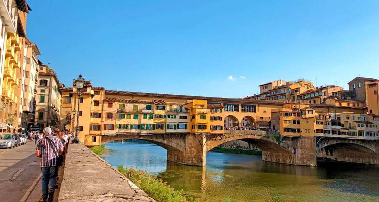 Iconic Ponte Vecchio bridge spanning the Arno River with warm evening light on historic Florence buildings.