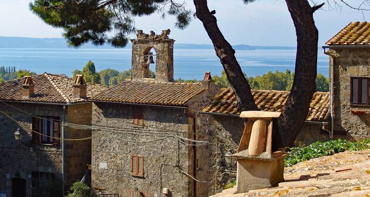 Stone village with tiled roofs and a bell tower overlooking a blue lake