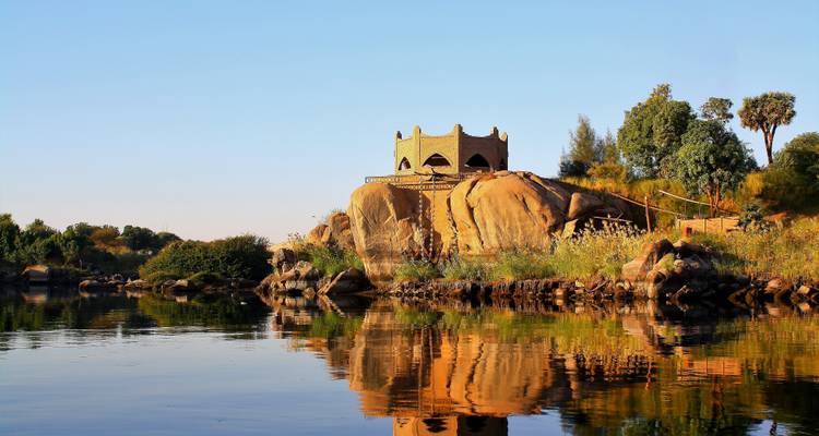 Rocks and a traditional building on a small island with water reflection.