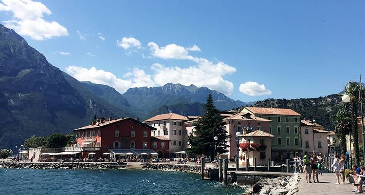Seepromenade mit bunten Gebäuden und Bergen.