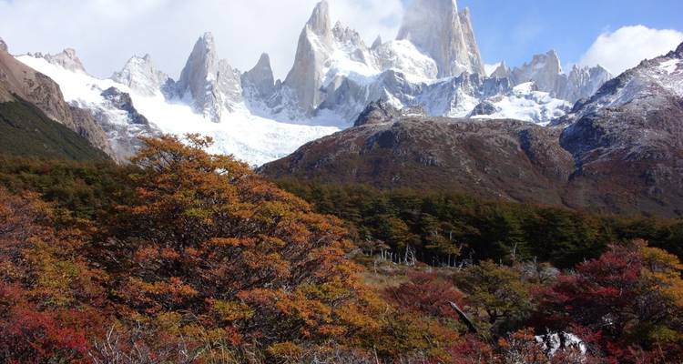 Mountains with snow-covered peaks and autumnal trees.