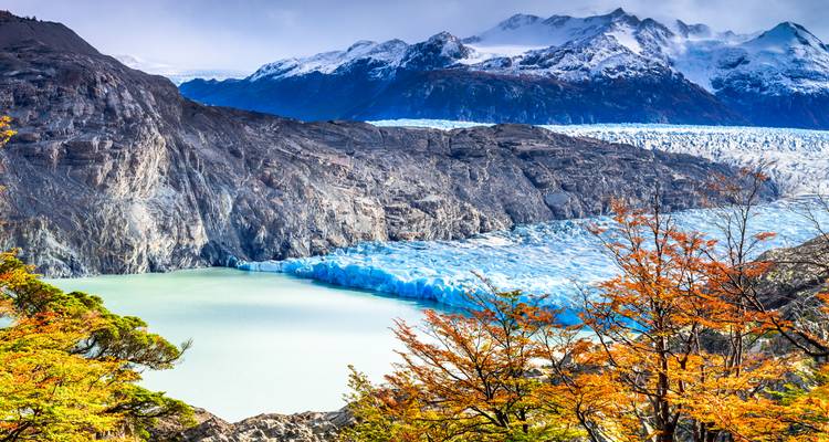 Paisaje glacial con árboles otoñales coloridos.