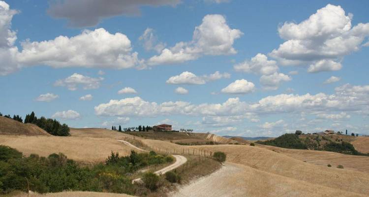 Hügelige Landschaft mit Wolken darüber.