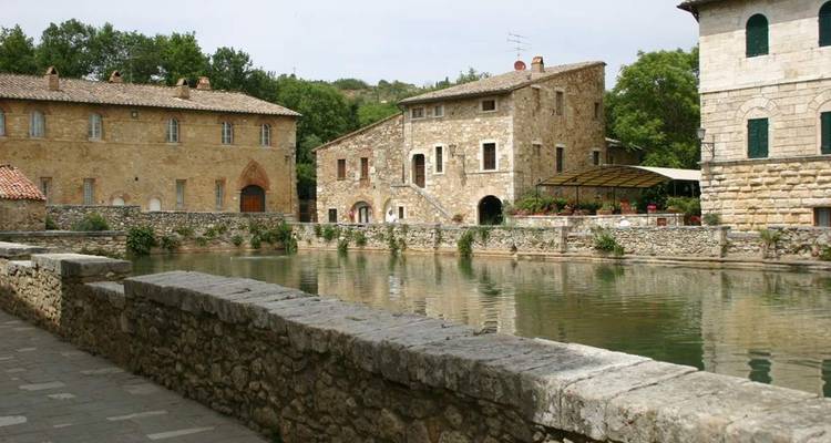 Charmant village avec des bâtiments historiques en pierre et un point d'eau.