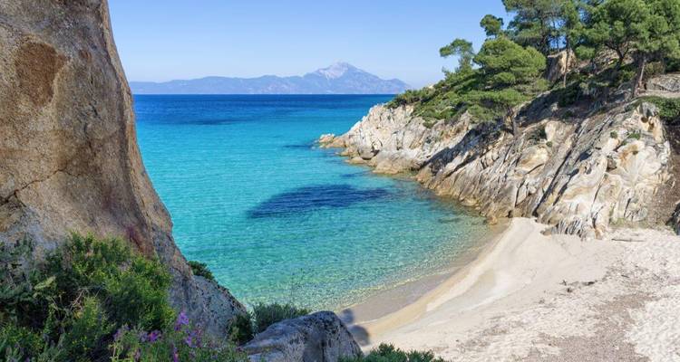 Eau turquoise claire avec des falaises rocheuses et une plage de sable.