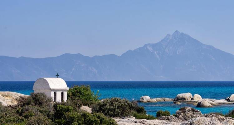 Weiße Kapelle am Strand mit Blick auf entfernte Berge.
