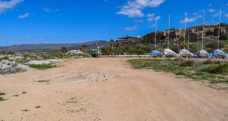 Yachts et cale sèche le long de la plage avec des collines en arrière-plan.