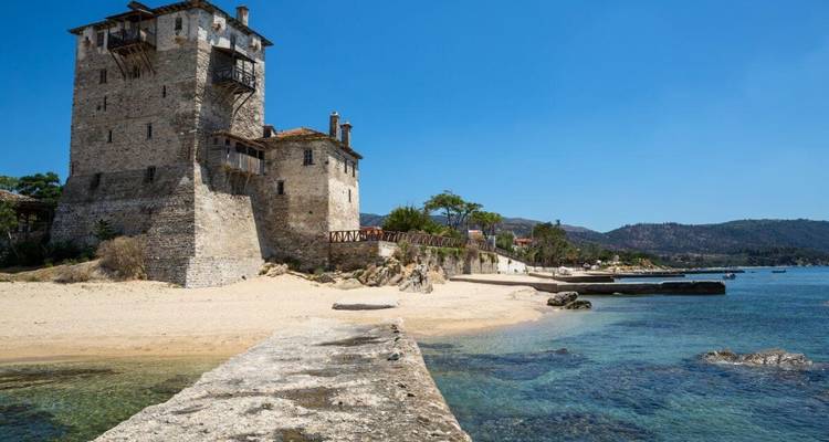Tour côtière historique à côté d'une plage sereine sous un ciel dégagé.
