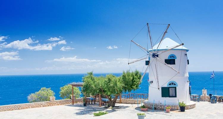Moulin à vent surplombant la mer sous un ciel bleu dégagé.