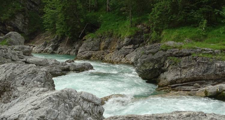 Fluss, der durch felsiges Gelände mit Grün fließt.