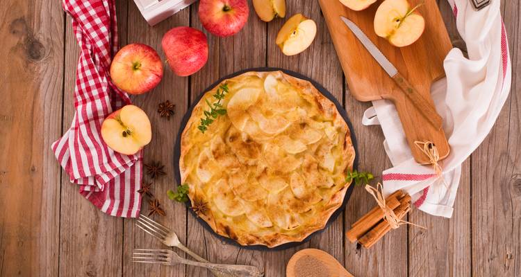 Apple pie with apples and cinnamon on a rustic table.