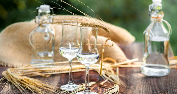 Glasses and bottles with hay on a wooden table.