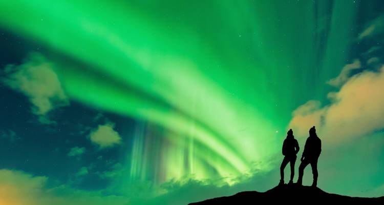 Zwei Personen als Silhouetten vor Nordlichtern.