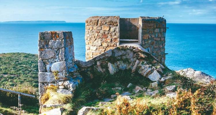 Ruines historiques sur une falaise avec la mer en arrière-plan.