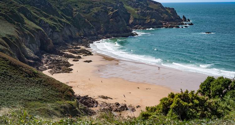 Plage de sable avec falaises et vagues de l'océan.