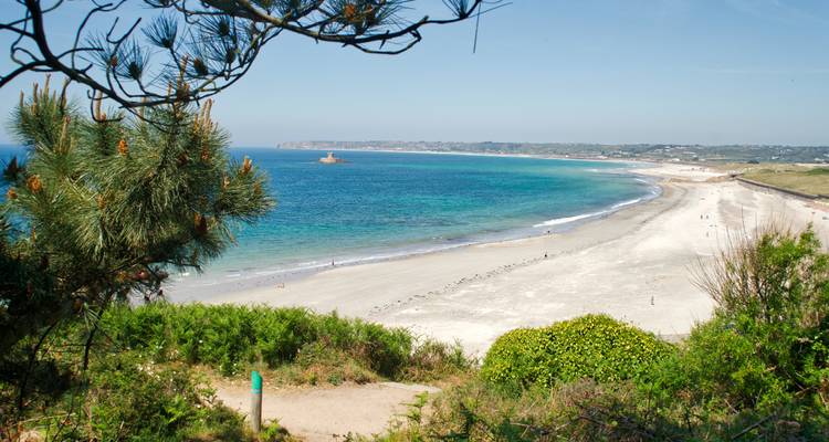 Large plage de sable avec une eau bleue claire.