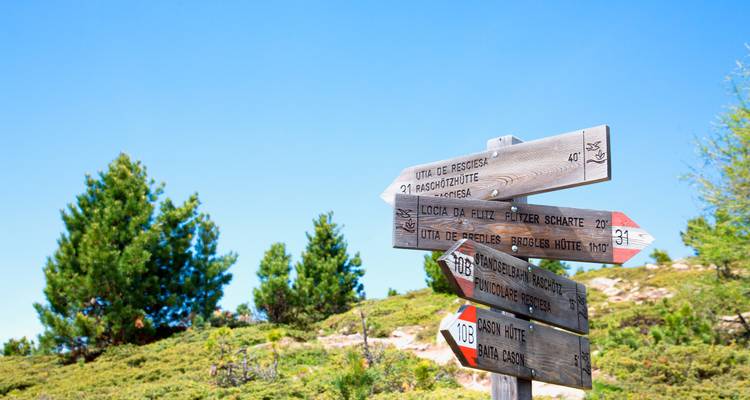 Gros plan d'un panneau de signalisation de montagne avec un ciel bleu dégagé.