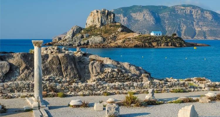 Ruines antiques avec colonnes au bord de la mer sous un ciel dégagé.