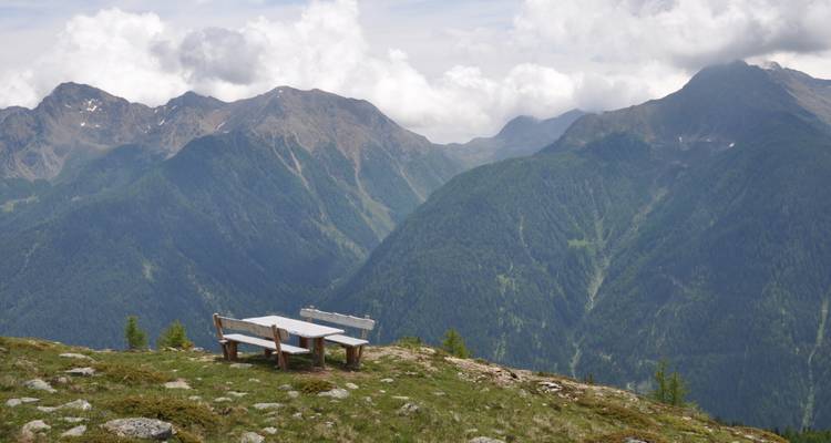 Blick auf Berge mit einer Bank im Vordergrund.