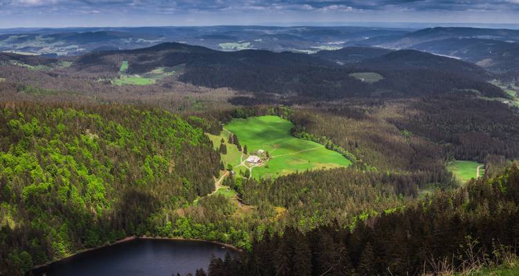 Expansive view of forested hills and a small lake.